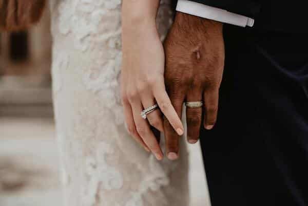 Novios en su boda, juntando sus manos. Cada uno porta un anillo de matrimonio.