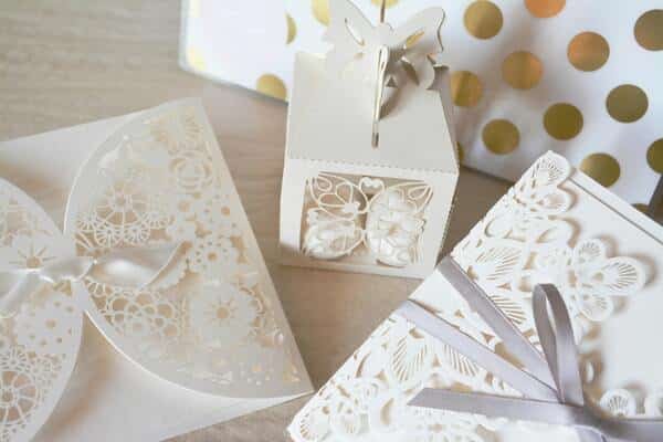 Invitaciones de boda, blancas, decoradas con lazos y mariposas.