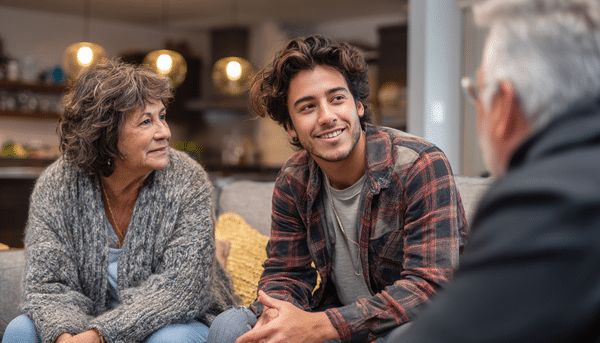 Hombre joven platicando con una pareja de edad mayor sobre la sala de una casa moderna.