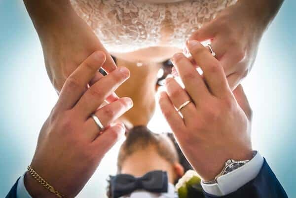 Pareja recién casada tomándose de las manos y besándose.